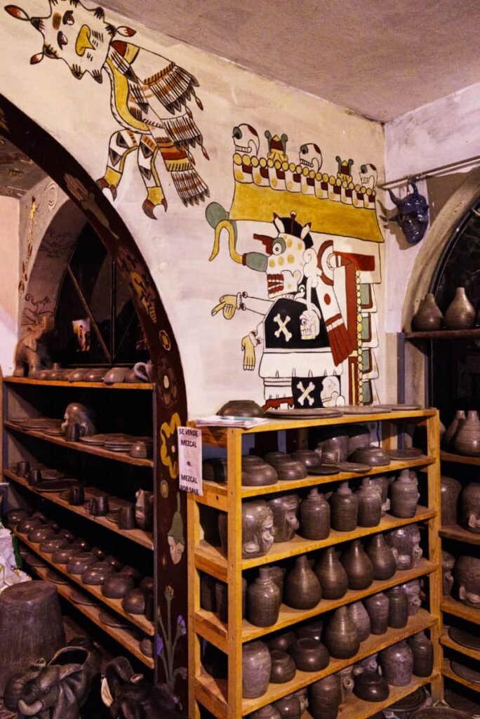 Finished pottery pieces line the shelves inside Paco's home. Above are Zapotec depictions on the walls.