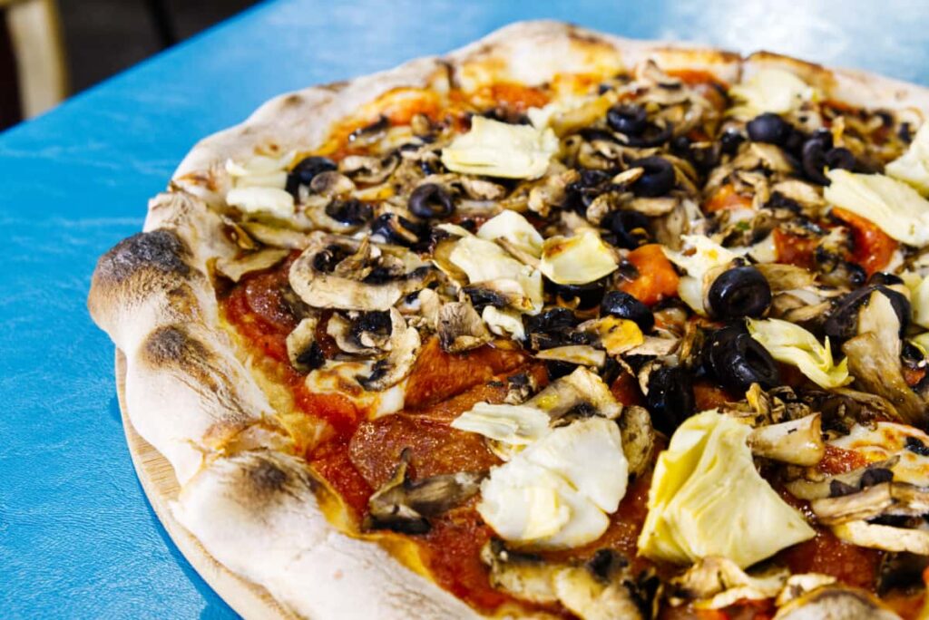 The best pizza in Puerto Escondido features a homemade crust, perfectly baked with toppings of pepperoni, mushrooms, olives, and artichoke hearts.