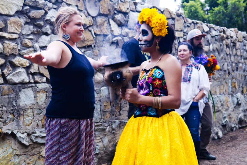 To start our dia de los muertos experience, Andrea cleanses us individually. Her face is painted like a catrina, her top is black with embroidered flowers. The marigold flower headband and skirt add a bright color of yellow.