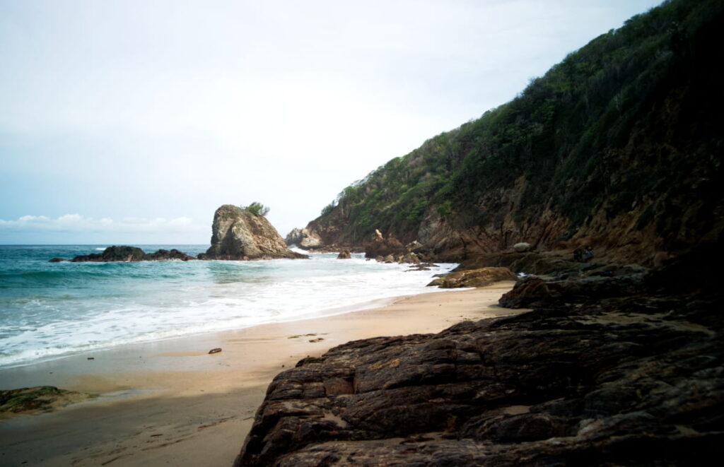 Blue ocean water flows into the rocks which curve around the corner to give Playa Rinconcito its name.