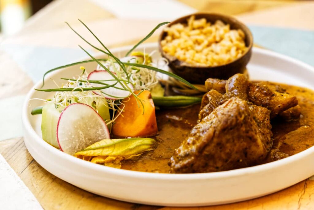 At Casa Taviche, one of the best places to eat in Oaxaca, the main course is a round plate with large pieces of vegetables, a small bowl of rice and pork ribs in a sauce.