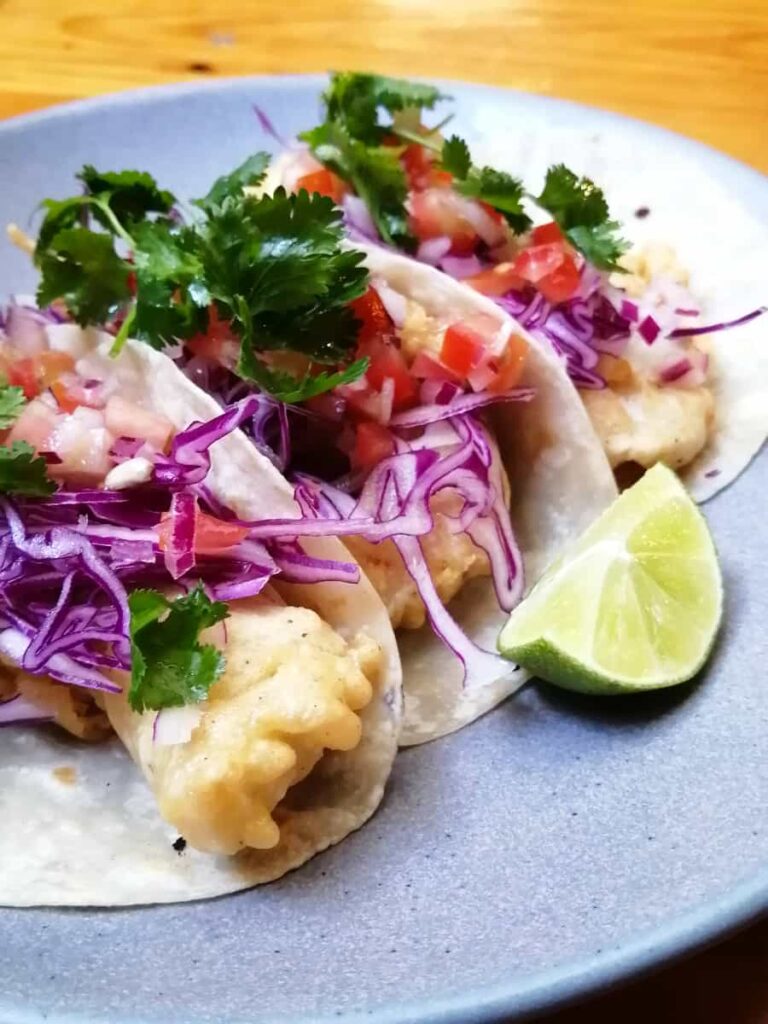 A plate of three breaded fish tacos with shredded purple cabbage, cilantro, and lime at La Rambla Restaurant in Oaxaca.