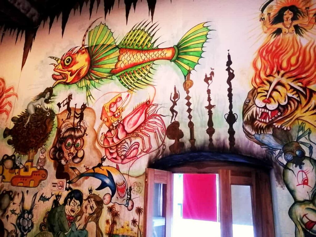 At one of the best Asian restaurants in Oaxaca, colorful cartoon like characters are painted on the white wall surrounding the doorway.