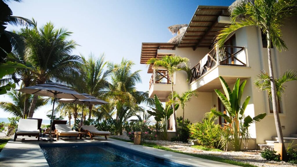 Casa Kuaa, one of the best places to stay in Puerto Esconddio features bungalows surrounding a pool with sun loungers. The upper level rooms have a balcony with wooden railing.