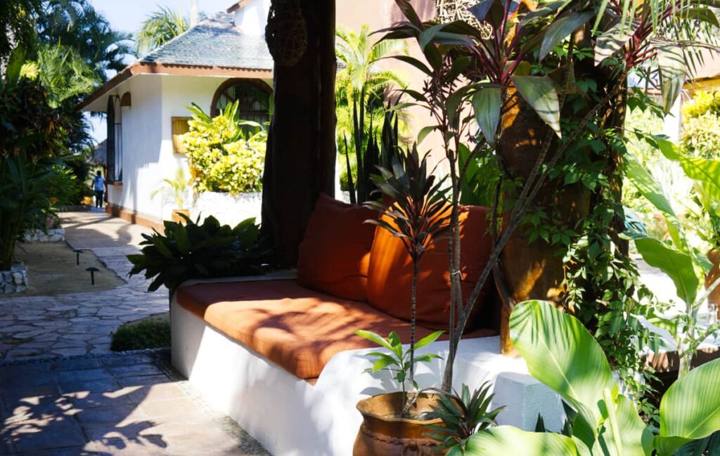 Orange cushions line bench seating surrounded by plants at Villas Carrizalillo.