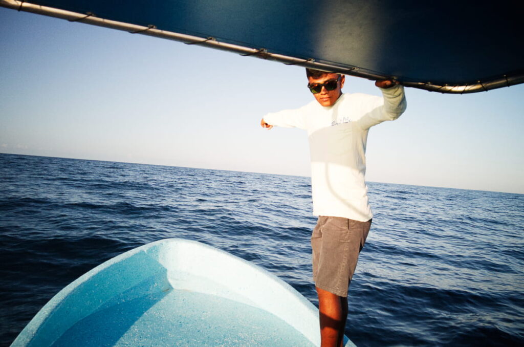 A young man stands at the bow of the boat as a spotter for whale watching in Puerto Escondido.