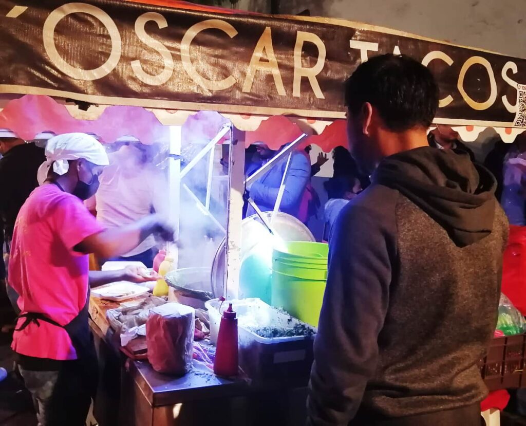 At night, a man serves a customer at D'Oscar Tacos - one of the best late night taco spots in Oaxaca.