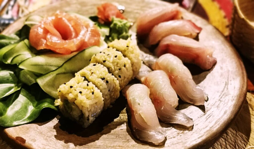 A plate of the best sushi in Puerto Escondido at Amazul Restaurant. It includes sashimi, 6 pieces of nigiri, and a sushi roll with a side of thinly sliced cucumbers.