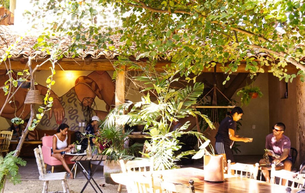 From the garden seating at Sandala Cafe in Puerto Escondido, several people drink coffee and eat breakfast as well as do remote work.