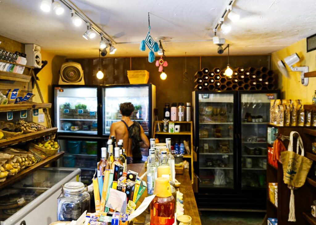 A shirtless man shops at Moringa, a vegan store in La Punta, Puerto Escondido. In the foreground are various vegan food products.