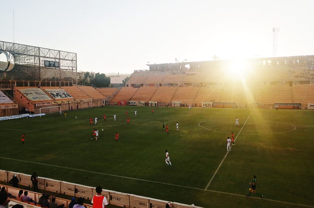 The sun cuts through the soccer stadium, one of the fun things to do in Oaxaca as the players run across the field.