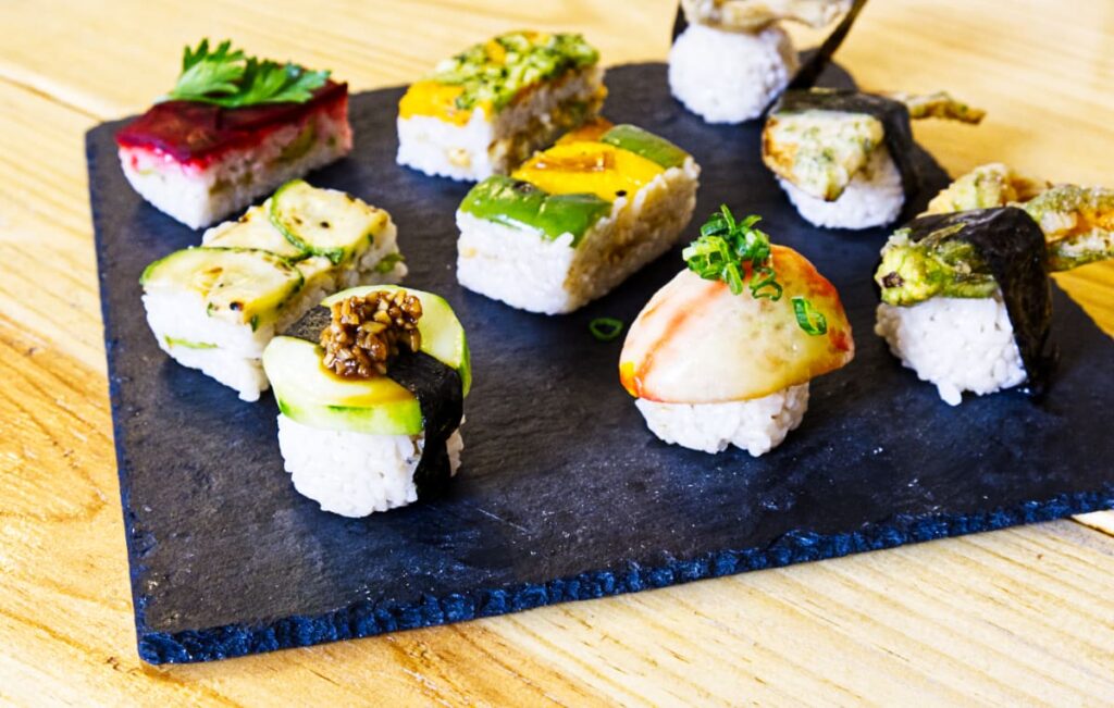 The best vegan sushi in Oaxaca is served on a square piece of slate as the plate. Each piece of vegan sushi features a vegan food item seasoned to taste like sushi.