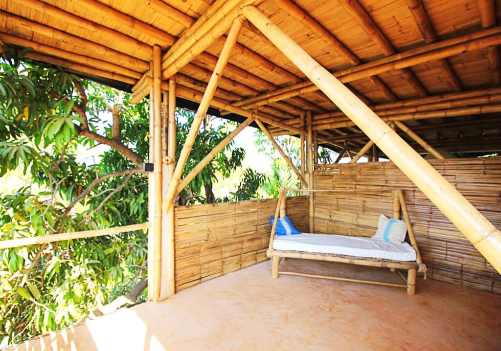 A bench made of bamboo sits on a private deck at Bambu Corner, a Puerto Escondido coliving space. The deck is framed in bamboo construction.
