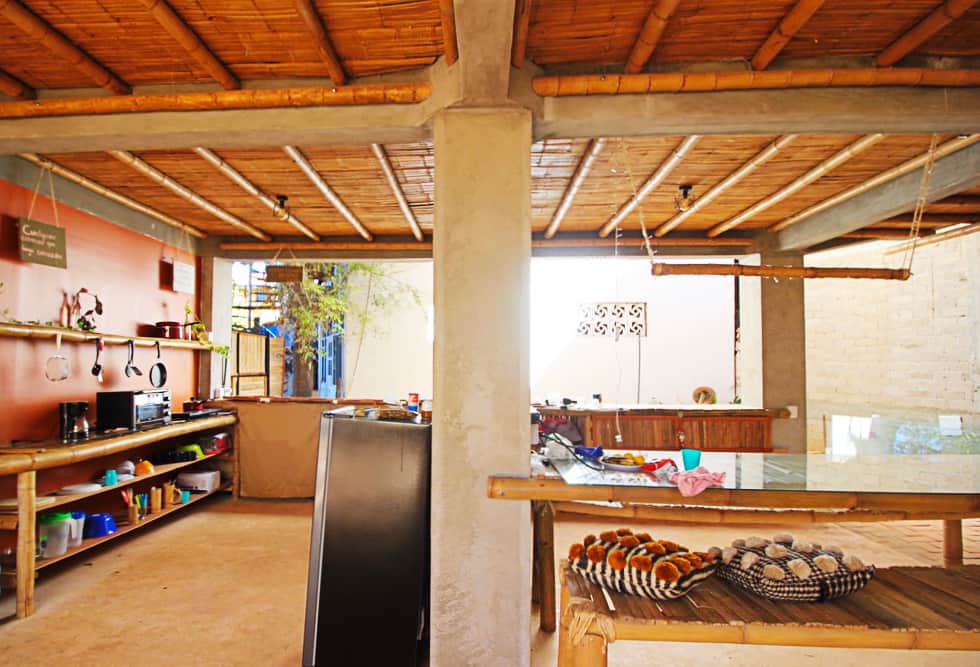 The wide open kitchen at Bambu Corner Coliving, Puerto Escondido includes bamboo countertops and shelves as well as a fridge, toaster over, and other kitchen essentials. The roof is entirely lined in bamboo pieces.
