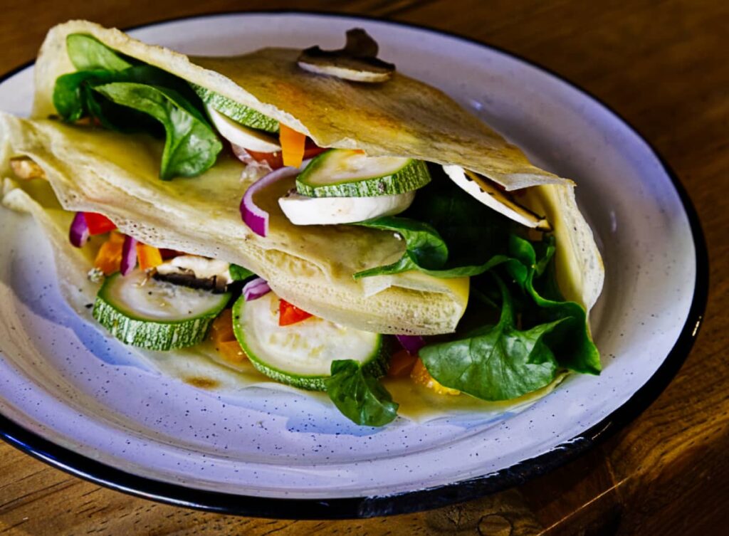 At one of the best Mazunte restaurants for vegetarian and vegan food, a fresh crepe filled with veggies and folded in a triangle sits on a white plate.