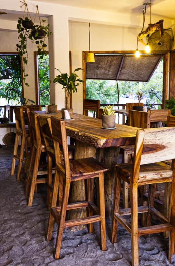At Nutopia Restaurant in Mazunte, tall wooden table and chairs sit on the sand floor.
