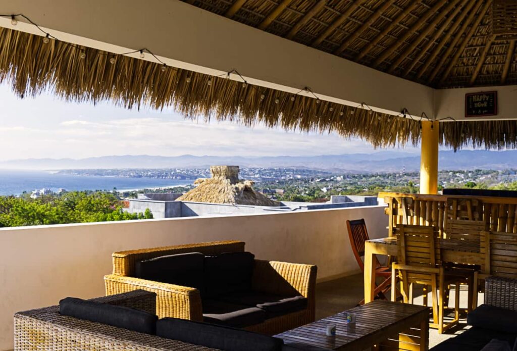 The rooftop at Bonobo features a palapa with sweeping views of the Puerto Escondido coastline with mountains in the background.