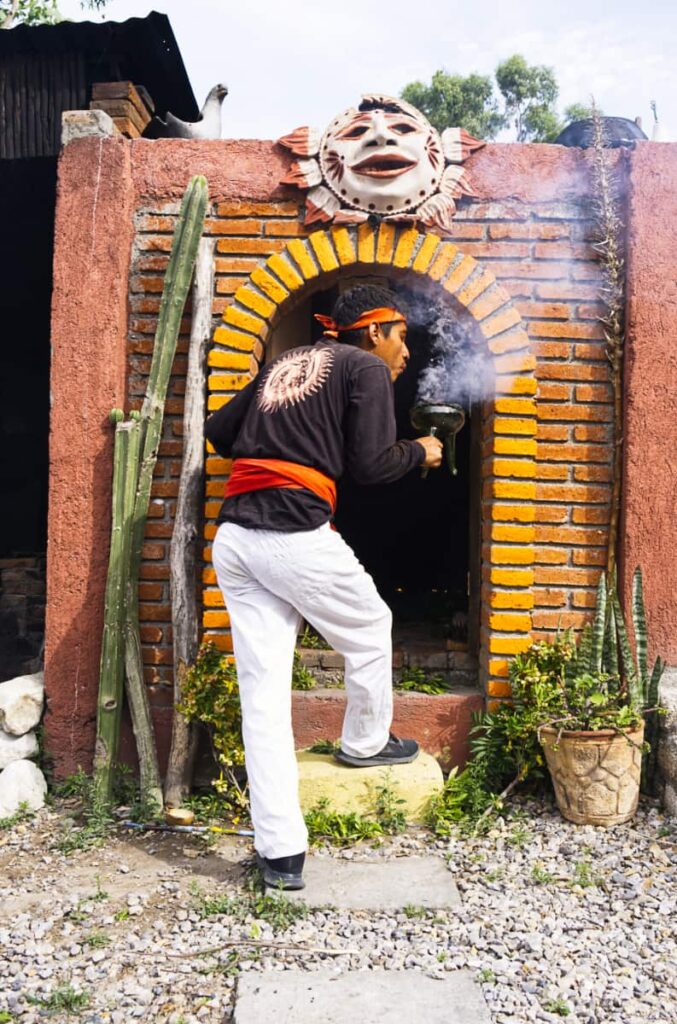 A young man blows smoke from a clay container of burning copal as he enters a small temazcal in Oaxaca.