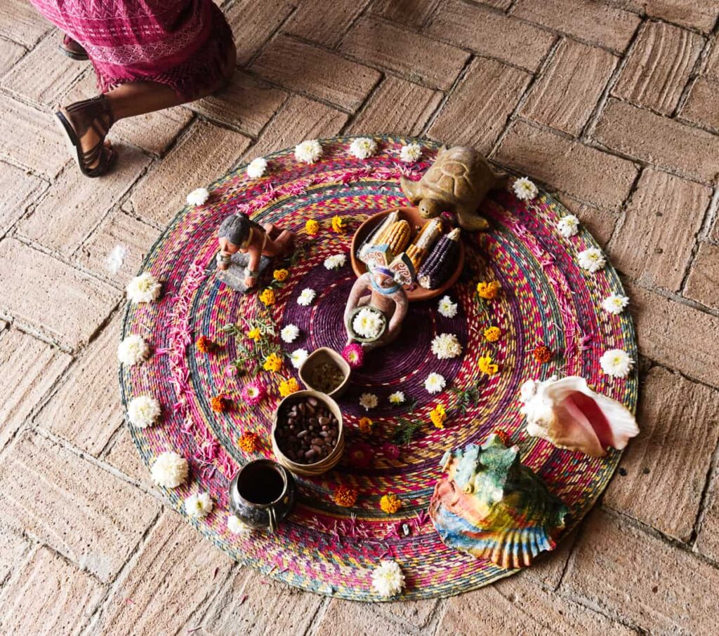 For the start of a Oaxaca temazcal, several items and flowers are thoughtfully placed on a colorful round rug as an offering to the spirits.