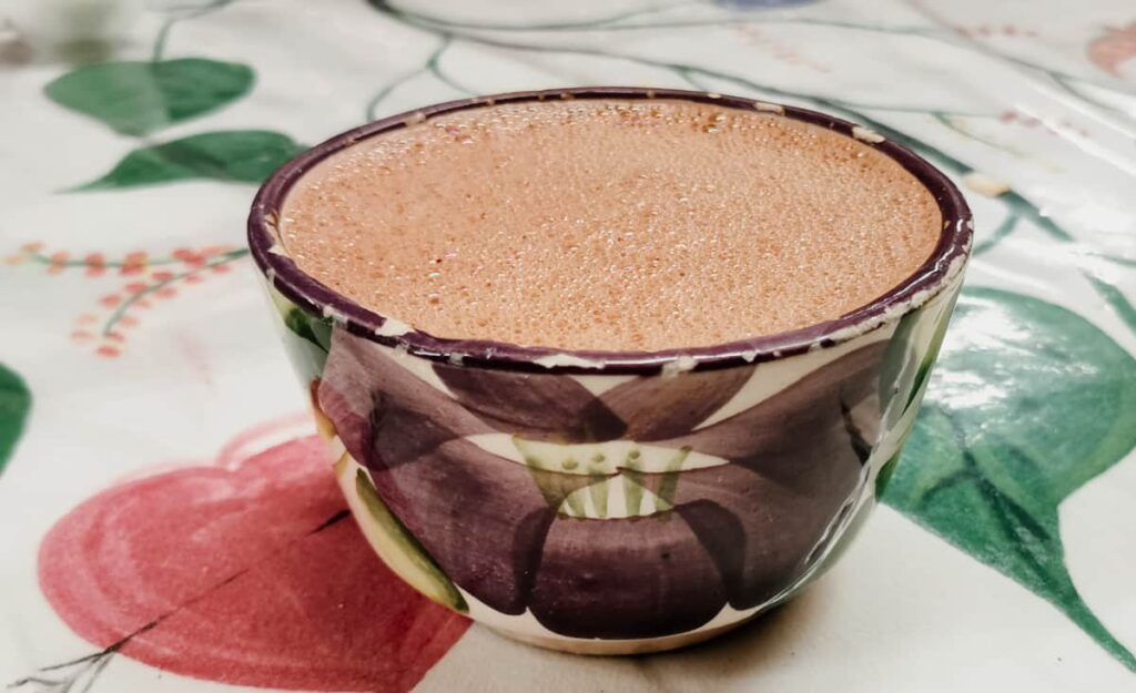 A frothy chocolate drink in Oaxaca which is served in a bowl decorated with a flower.