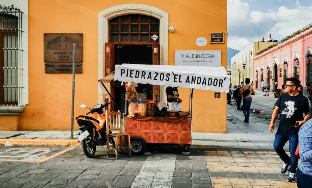 As people pass by, a street food stand advertises piedrazos, a Oaxacan snack.