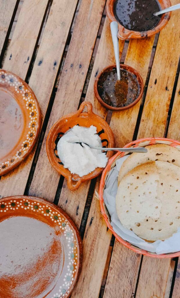 An overhead view of totopos istmo, fresh cheese, beans, and salsa. The totopos istmo are a traditional food from Oaxaca and feature small holes.