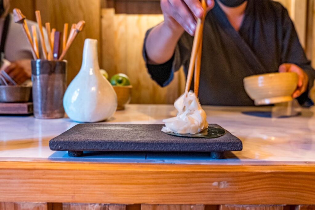 A man uses chopsticks to plate a piece of food at Crudo omakase in Oaxaca.
