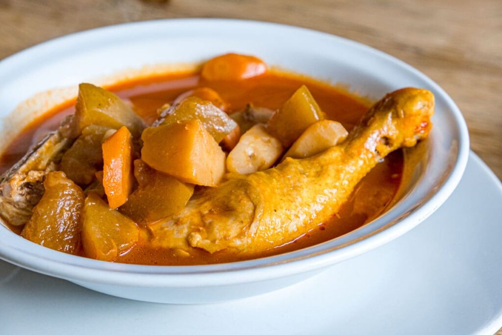 A chicken leg with potatoes, carrots, and chayote squash in a bowl of mole amarillo in a restaurant in Oaxaca.