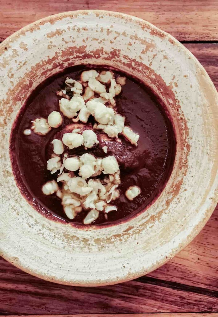 At Levadura de Olla restaurant in Oaxaca, an overhead view of mole coloradito topped with pieces of puffed corn.