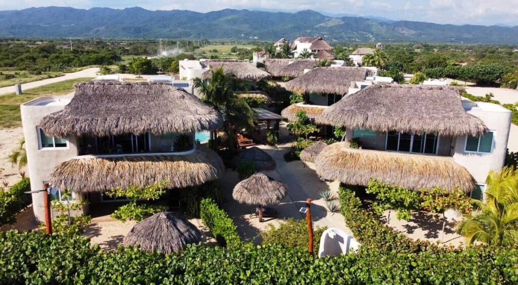 An overhead view of El Origen Villas & Spa featuring thatched roofs surrounded by lush greenery and palm trees.