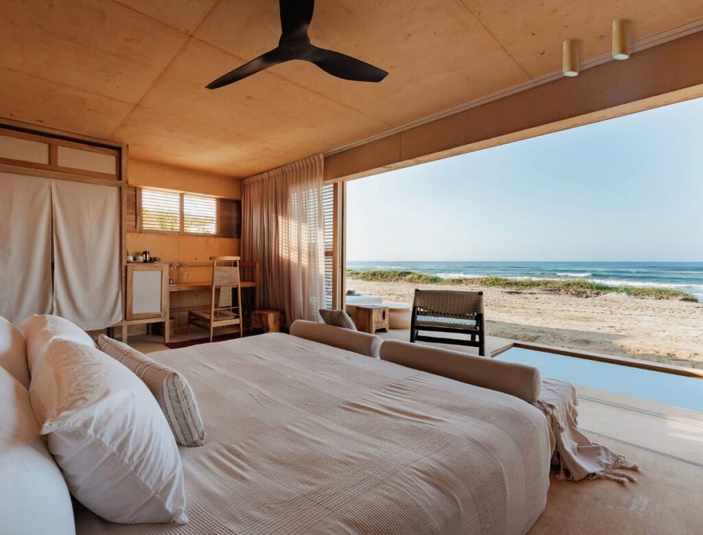 A view of the bedroom at KYMAIA that opens to a stunning beach view furnished with quality furnishings.