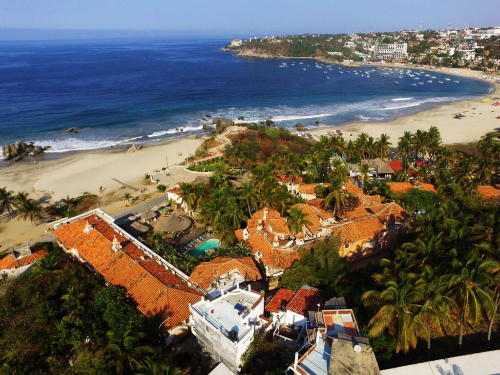 An overhead view of Hotel Santa Fe surrounded by lush greenery, palm trees and the nearby beach.