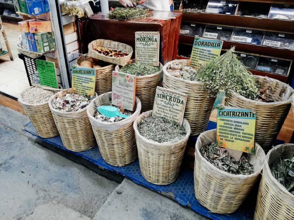 At a stall in the Abastos Market, woven baskets full of dried herbs blends are on display. Each blend is labeled with a sign to signify the name and benefits.
