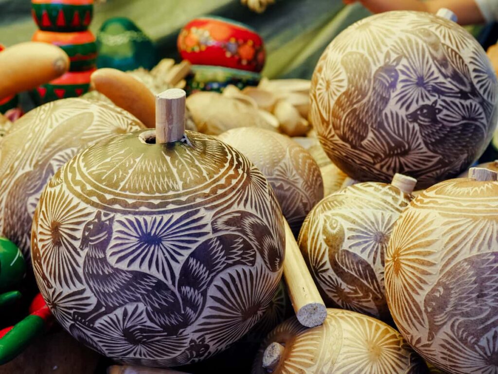 Carved gourds, one of the artisan items to buy at the markets in Oaxaca, sit on a table. The carvings feature various animals in different colors.
